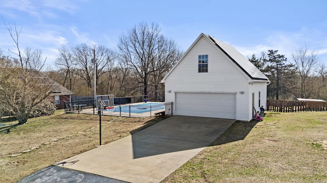 view of property exterior with a fenced in pool, fence, a yard, a garage, and an outbuilding