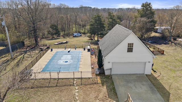 view of swimming pool featuring a forest view, a yard, and fence