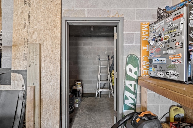 misc room featuring unfinished concrete floors and concrete block wall