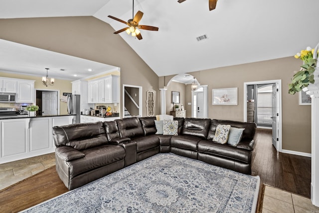 living area with visible vents, ornate columns, high vaulted ceiling, arched walkways, and ceiling fan with notable chandelier