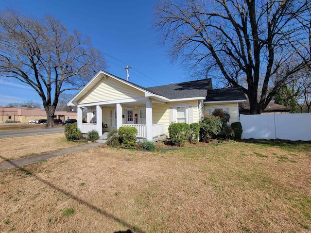 view of front of property featuring covered porch, a front yard, and fence