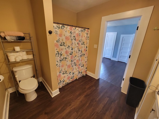 full bath featuring curtained shower, toilet, wood finished floors, and baseboards