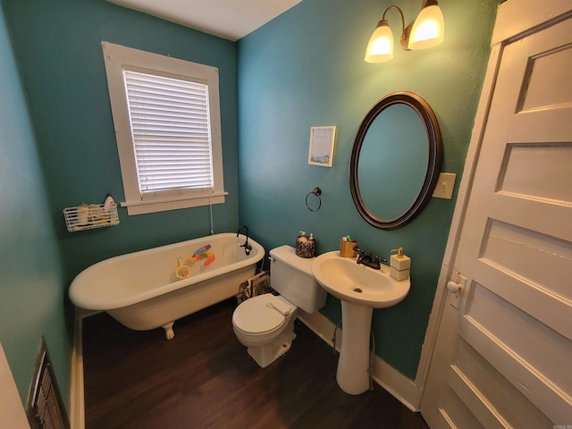 full bath featuring a soaking tub, toilet, wood finished floors, and baseboards