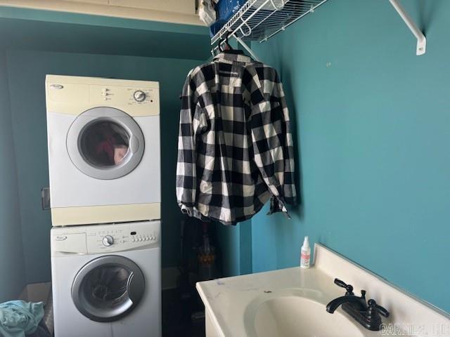 washroom with laundry area, stacked washer and dryer, and a sink