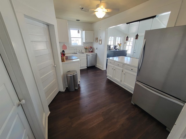 kitchen with dark wood finished floors, stainless steel appliances, white cabinets, light countertops, and hanging light fixtures