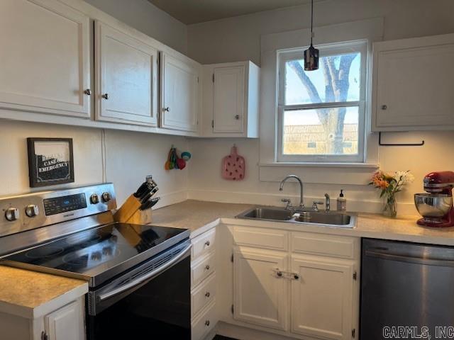 kitchen featuring pendant lighting, a sink, appliances with stainless steel finishes, white cabinets, and light countertops