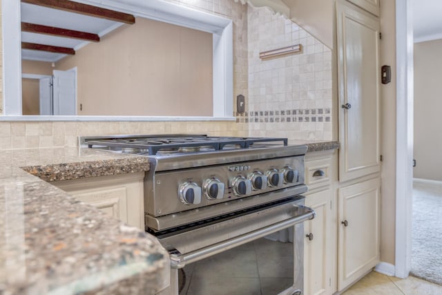 kitchen featuring light stone counters, light tile patterned floors, ornamental molding, high end stainless steel range, and tasteful backsplash