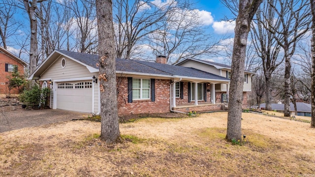 view of front of house with aphalt driveway, a porch, a garage, brick siding, and a chimney