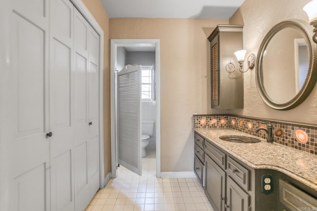 bathroom with tile patterned flooring, backsplash, baseboards, toilet, and vanity