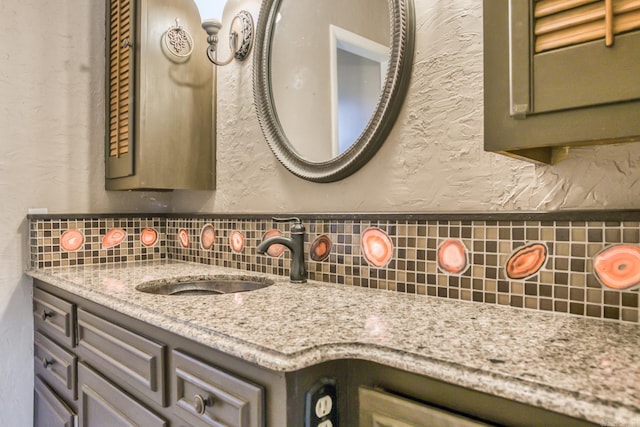 bathroom with backsplash, vanity, and a textured wall