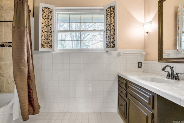 bathroom with a wainscoted wall, tile walls, vanity, and tile patterned flooring