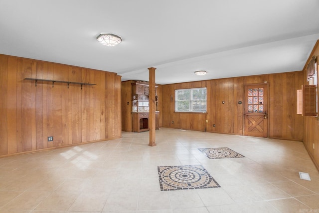 interior space featuring decorative columns, baseboards, and wood walls