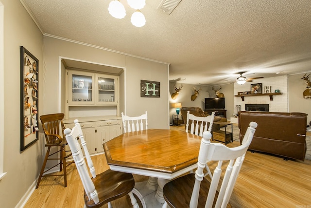 dining room with ceiling fan, visible vents, light wood-style flooring, and a fireplace