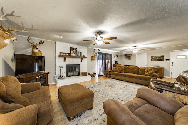 living room with a textured ceiling, a brick fireplace, and light wood finished floors