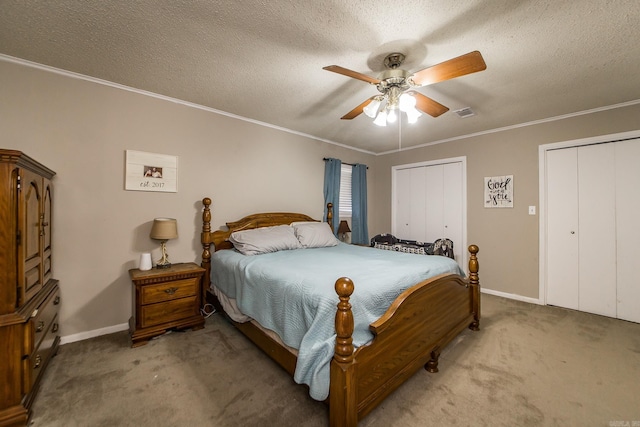 bedroom with a textured ceiling, crown molding, multiple closets, and light carpet