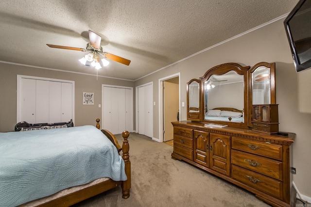 bedroom with two closets, light colored carpet, ornamental molding, and a textured ceiling