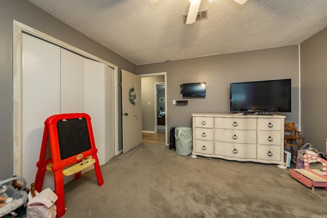 playroom featuring visible vents, light carpet, a textured ceiling, and ceiling fan