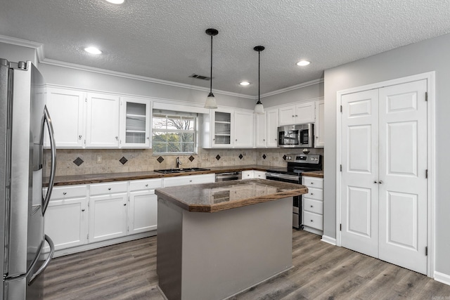 kitchen featuring a sink, stainless steel appliances, dark countertops, and dark wood-style floors