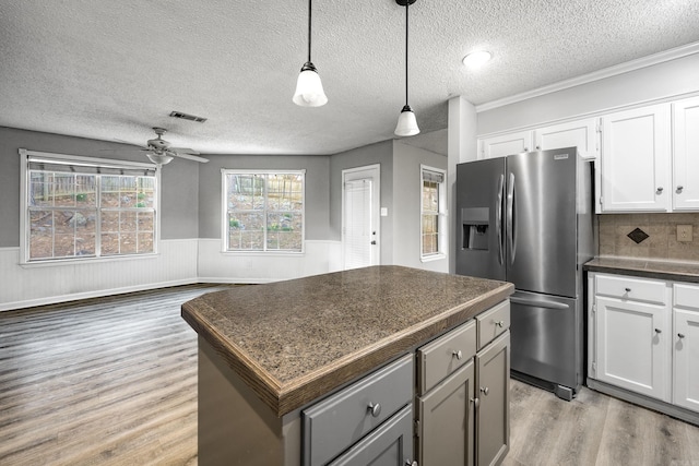 kitchen with visible vents, stainless steel fridge with ice dispenser, light wood-style floors, wainscoting, and a center island