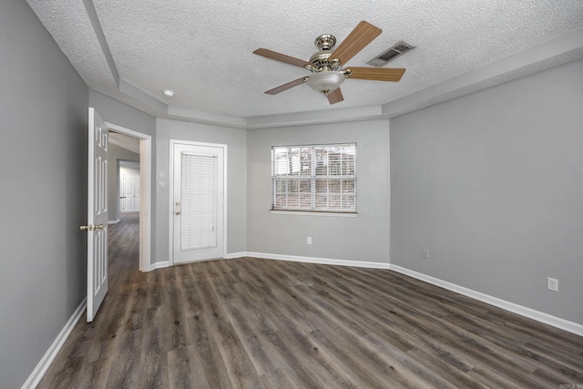 empty room with visible vents, baseboards, a textured ceiling, and dark wood-style flooring