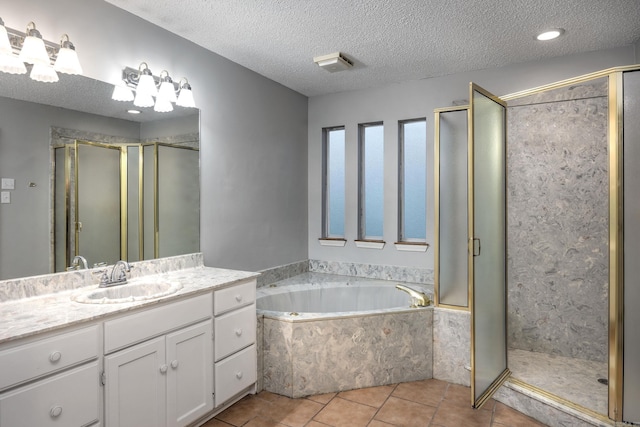 bathroom with vanity, a shower stall, a garden tub, and a textured ceiling