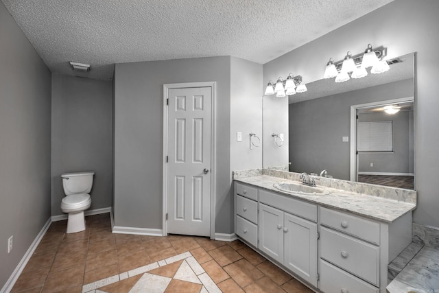 bathroom with vanity, baseboards, tile patterned flooring, a textured ceiling, and toilet