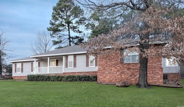 ranch-style house with brick siding, covered porch, a front yard, and a shingled roof