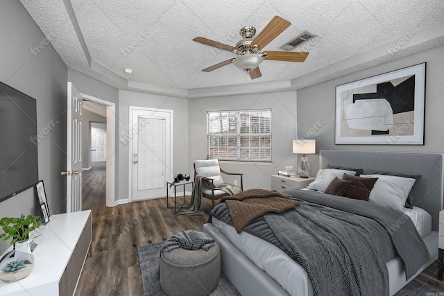 bedroom with visible vents, baseboards, wood finished floors, a raised ceiling, and a ceiling fan