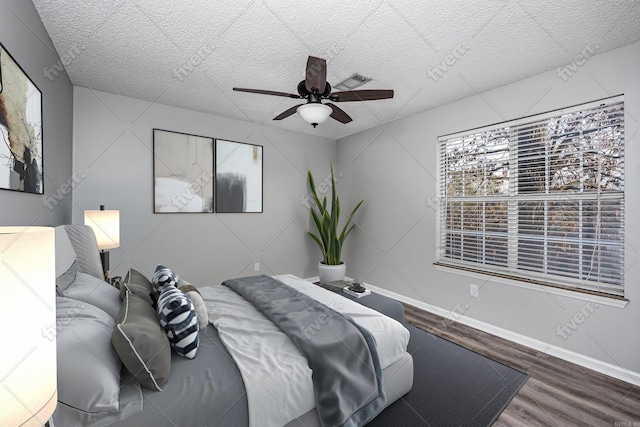 bedroom featuring baseboards, a textured ceiling, ceiling fan, and wood finished floors