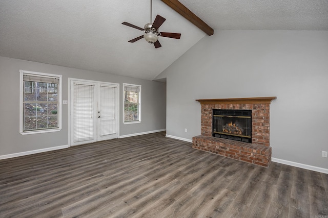 unfurnished living room with wood finished floors, baseboards, lofted ceiling with beams, a textured ceiling, and a brick fireplace