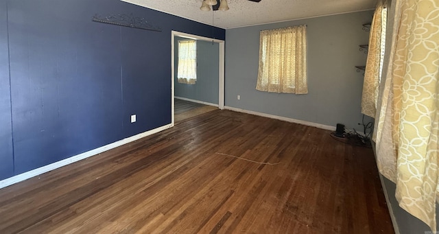 spare room with a textured ceiling, a ceiling fan, baseboards, and wood finished floors