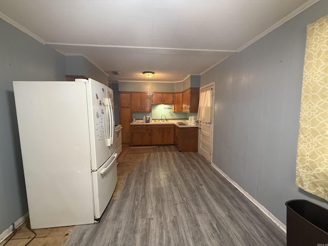 kitchen with freestanding refrigerator, ornamental molding, light countertops, dark wood-type flooring, and brown cabinets