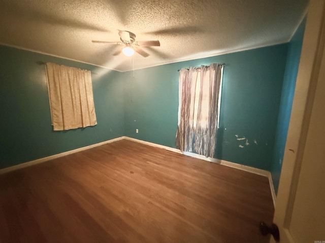 unfurnished bedroom with ceiling fan, a textured ceiling, baseboards, and wood finished floors