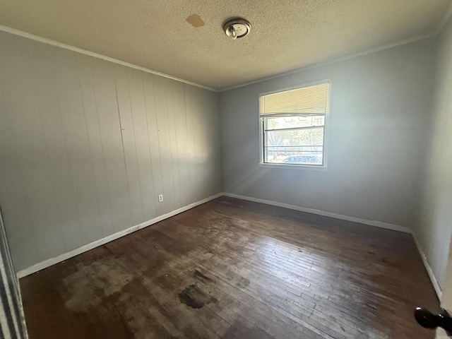 spare room with baseboards, a textured ceiling, dark wood-style flooring, and crown molding