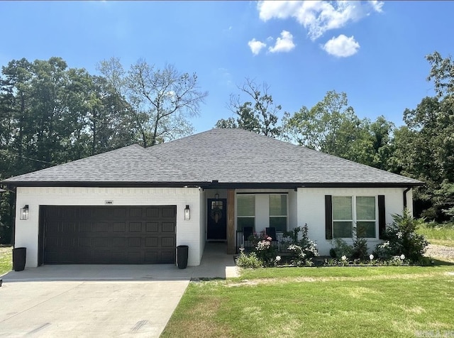 ranch-style home featuring a front yard, a garage, driveway, and roof with shingles