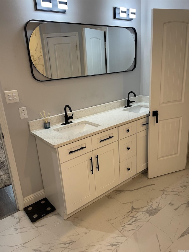 full bath featuring double vanity, baseboards, marble finish floor, and a sink