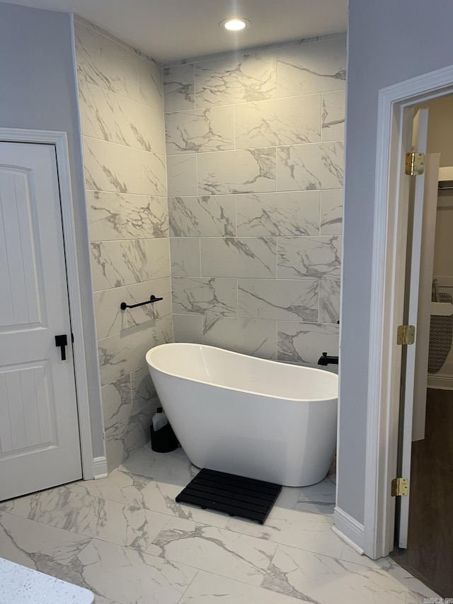 full bathroom featuring recessed lighting, marble finish floor, and a freestanding tub