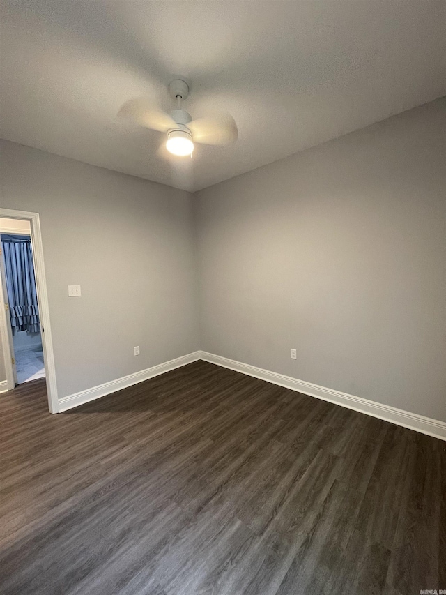 unfurnished room featuring baseboards, dark wood-style floors, and a ceiling fan