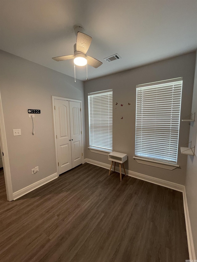 unfurnished bedroom featuring dark wood-type flooring, baseboards, visible vents, and ceiling fan