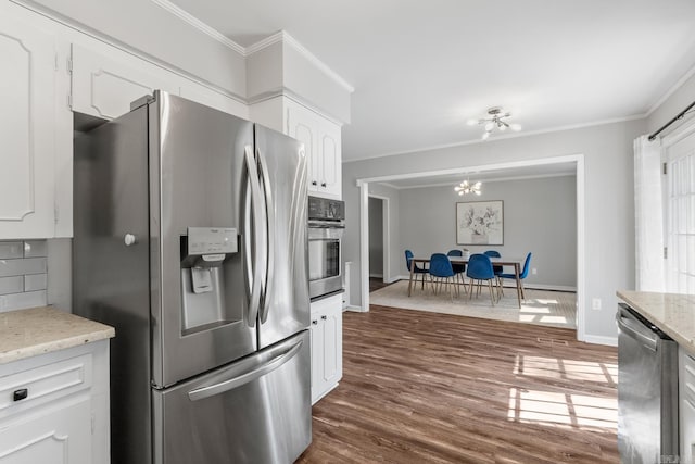 kitchen featuring crown molding, baseboards, dark wood-type flooring, appliances with stainless steel finishes, and white cabinetry