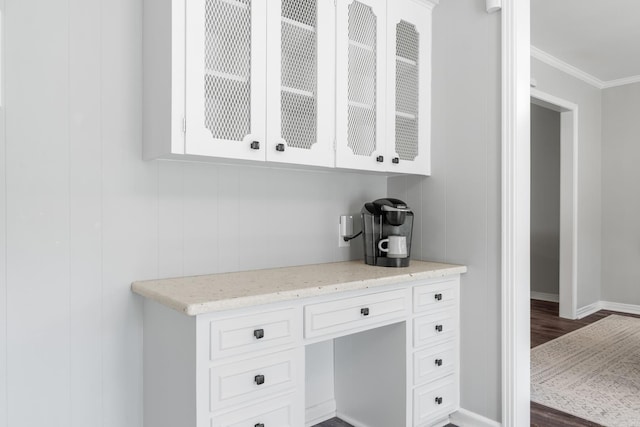 bar with dark wood finished floors, built in study area, baseboards, and ornamental molding