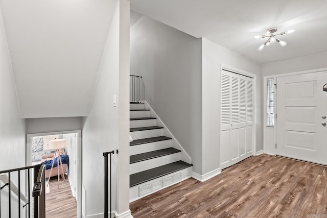 foyer with wood finished floors, visible vents, baseboards, stairs, and a notable chandelier