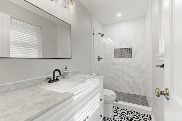 bathroom featuring toilet, tiled shower, and vanity