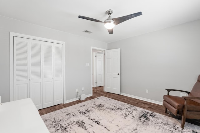 bedroom featuring wood finished floors, baseboards, visible vents, and a closet