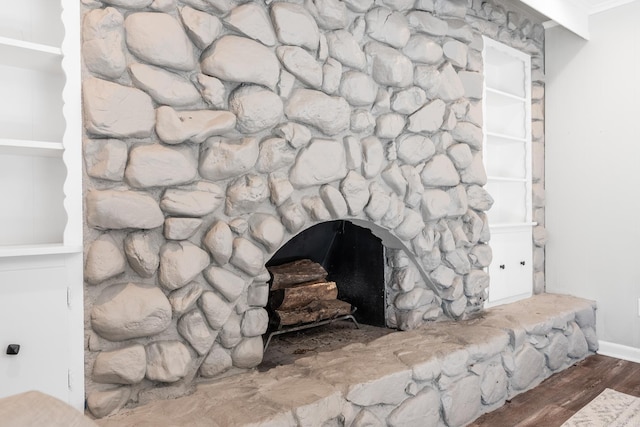 interior details featuring a stone fireplace and wood finished floors