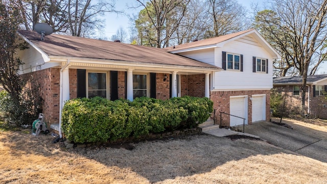 tri-level home with a porch, an attached garage, brick siding, and driveway