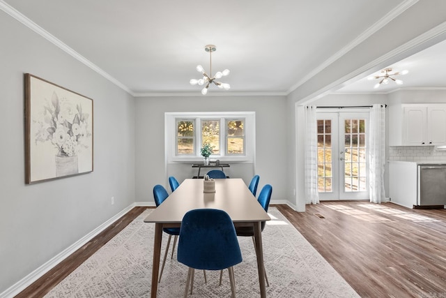 dining space featuring french doors, dark wood-type flooring, a notable chandelier, and ornamental molding