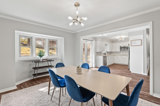 dining space with a chandelier, crown molding, baseboards, and wood finished floors