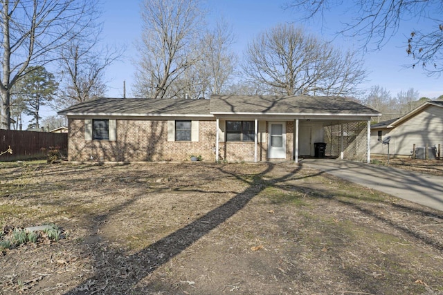 single story home featuring concrete driveway, fence, brick siding, and a carport