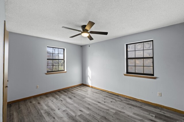 unfurnished room with ceiling fan, wood finished floors, baseboards, and a textured ceiling